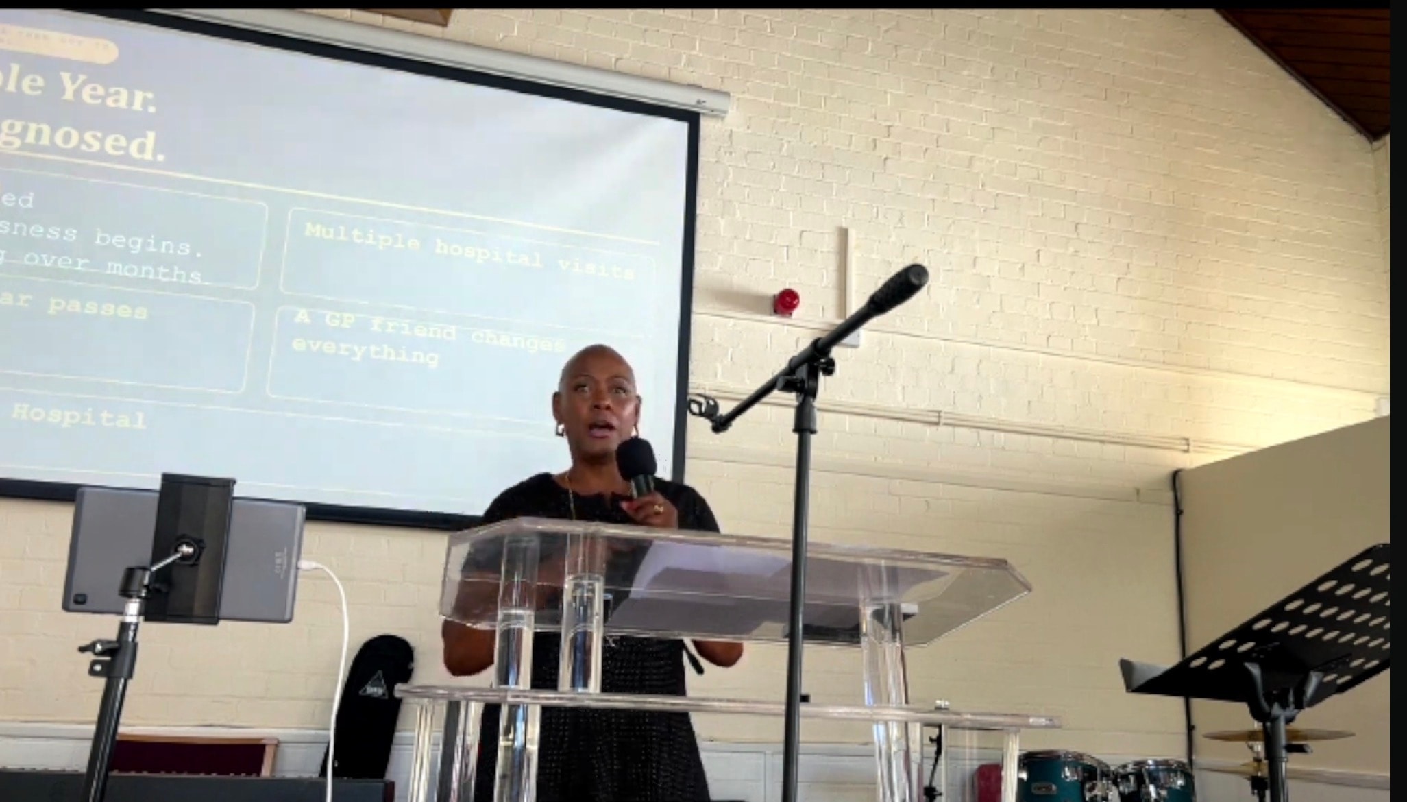 Sharon-Ann Phillips speaking at True Vine church with a presentation slide visible behind her